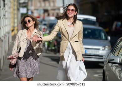 Excited Happy Women Walking Together On The Street. Happy Beautiful Women Friends In Fashion Dress Walking And Running Joyful And Cheerful Smiling In City.