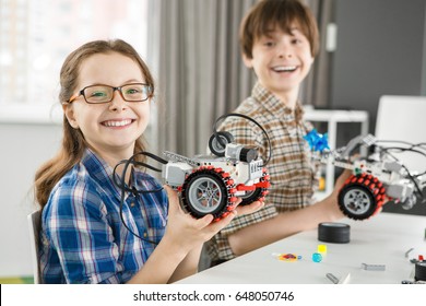 Excited And Happy Young Cute Girl Smiling To The Camera Holding Her Electronic Robot Copyspace Her Brother Posing With His Robot On The Background Education Learning Science Children Creativity Study