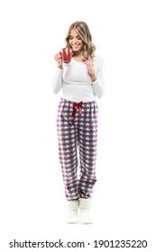 Excited Happy Young Woman Waking Up Drinking Coffee In Pajamas And Cozy Socks. Full Length Portrait On White Background.