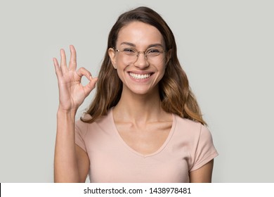 Excited Happy Young Woman Wearing Glasses Showing Ok Gesture With Fingers, Attractive Female, Satisfied Client With Wide Toothy Smile Recommend Good Service, Standing Isolated On Studio Background