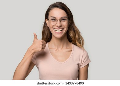 Excited Happy Young Woman Wearing Glasses Showing Thumbs Up, Attractive Female With Healthy Smile Looking At Camera, Satisfied Client Customer Recommend Service, Isolated On Studio Background