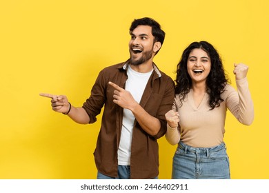 Excited Indian Couple Pointing and Celebrating on Yellow Background - Powered by Shutterstock