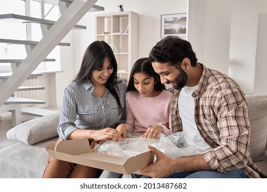 Excited Indian Family With Child Daughter Unpack Parcel At Home. Happy Parents And Teen Kid Daughter Open Postal Box Receive Present Gift In Online Shopping Delivery Package Sitting On Sofa Together.