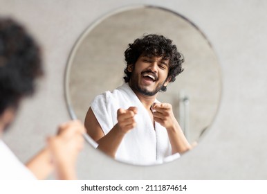 Excited Indian Guy Pointing At Mirror In Bathroom With Two Fingers, Standing With Towel On Shoulder And Smiling To His Reflection, Free Space. Champion's Morning Concept