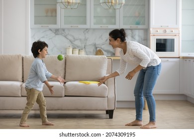 Excited Indian mom playing active games with little son at home, throwing ball to kid in living room, enjoying leisure with preschool boy. Babysitter watching child, practicing activity on playtime