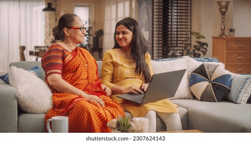 Excited Indian Mother and Daughter Using Laptop: Bonding Over Shared Interests, Doing Online Shopping for best e-Commerce Deals and Clothing Sales. Celebrating Family Togetherness. - Powered by Shutterstock