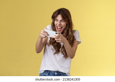 Excited Intense Playful Gamer Girl Geek Playing Awesome Smartphone Game Hold Mobile Phone Horizontal Grimacing Eager Win Arcade Stare Screen Tap Display Stand Yellow Background Tilting