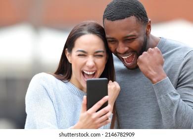 Excited Interracial Couple Checking Smart Phone In The Street