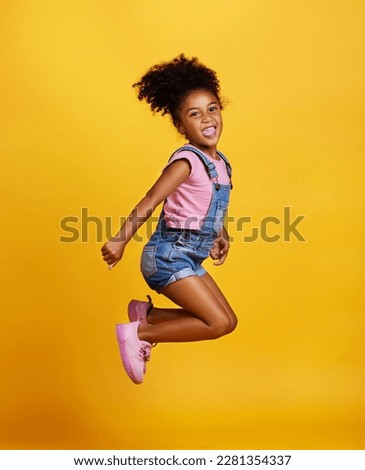 Excited, jump and happy girl child jumping in happiness, joy and smile while isolated in a studio yellow background. Energy, celebrate and kid in the air due to winning, celebrating and succuss