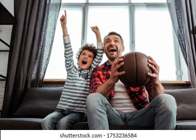 Excited Kid And Father Holding Basketball While Watching Championship