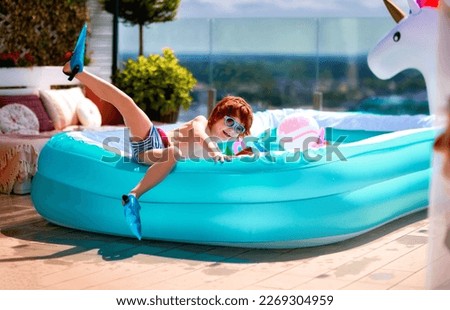 excited kid having fun sitting on inflatable pool on summer patio
