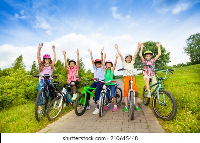 Excited Kids In Helmets On Bikes With Hands Up