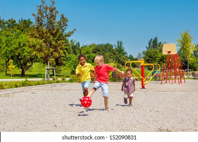 Begeisterte Kinder, die mit einem Ball auf dem Spielplatz laufen