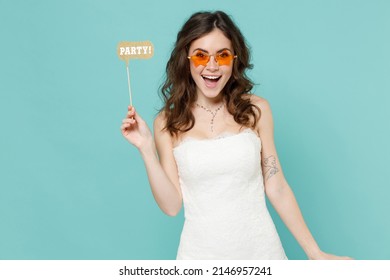 Excited laughing bride young woman 20s years old in beautiful white wedding dress glasses hold photo props isolated on blue turquoise background studio portrait. Ceremony celebration party concept - Shutterstock ID 2146957241