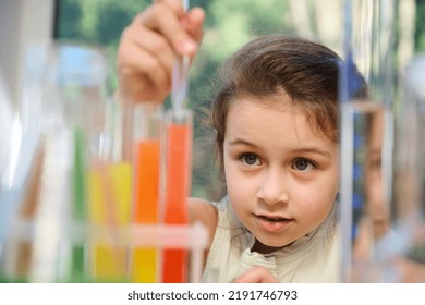 Excited Little Girl Using Chemistry Set In Elementary Science Classroom. Schoolgirl Making Scientific Experiments, Dripping Reagents Into A Test Tube With Chemicals. New Knowledge In New Academic