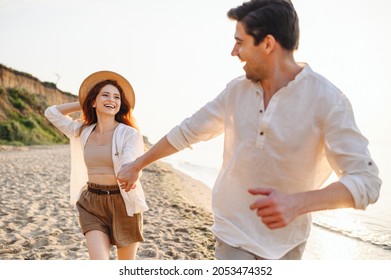 Excited Lovely Young Couple Two Friends Family Man Woman In White Clothes Hold Hands Running Walk Stroll Dance Together At Sunrise Over Sea Beach Ocean Outdoor Seaside In Summer Day Sunset Evening.