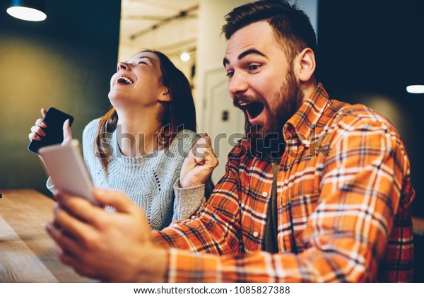 Excited male and female hipsters rejoice in\
winning an internet lottery made bets on website on modern\
smartphone.Happy couple in love celebrating victory in online\
competitions enjoying\
success