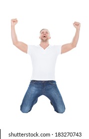 Excited man cheering in jubilation dropping down on his knees with his fists raised in the air as he celebrates a success  on white