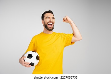 excited man holding soccer ball and screaming while showing win gesture isolated on grey - Shutterstock ID 2227053735