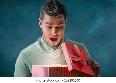 Excited Man Opening Big Gift Box Outdoors At Winter. Frost On His Face