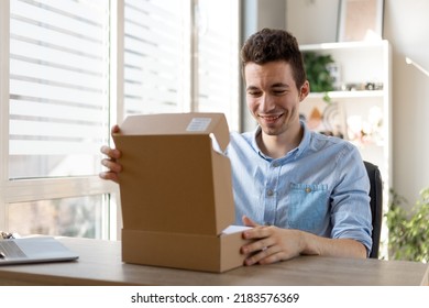 Excited man opening cardboard parcel box receiving gift sitting at home office desk. Overjoyed male consumer shopper unpacking postal delivery celebrating good online purchase concept.
 - Powered by Shutterstock