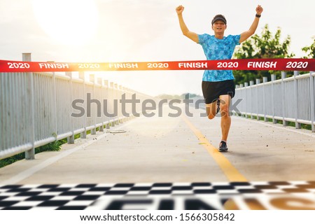 Excited man runner crossing the 2020 finish line of marathon. 2020 success concept