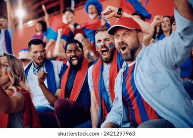 Excited man shouting while spectating sports match with group of fans at the stadium. 