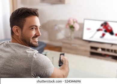 Excited man switch TV to ice hockey by remote control