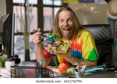 Excited Man In Tie Dye Shirt Eating Healthy Food At His Desk