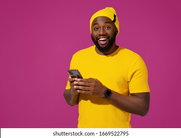 Excited man uses the phone on purple background