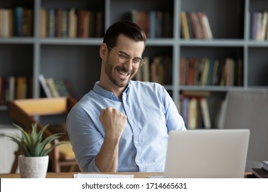 Excited man wearing glasses celebrating success, reading good news in email, happy overjoyed businessman looking at laptop screen, showing yes gesture and laughing, sitting at work desk - Shutterstock ID 1714665631