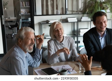 Excited mature businesspeople with colleagues eating pizza during break in office together, happy senior coworkers laughing at funny joke, talking chatting having fun, sharing corporate lunch - Shutterstock ID 2193930335