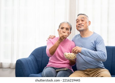 Excited Mature Couple, Senior Man And Woman Watching Tv, Senior Sport Fans Celebrating Favorite Team Victory, Sitting On Cozy Couch And Eating Popcorn Snack At Home, Enjoying Weekend. Happy Senior.