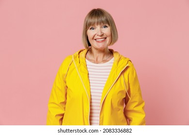 Excited Mature Elderly Senior Lady Woman 55 Years Old Wear Yellow Waterproof Raincoat Outerwear Isolated On Plain Pastel Light Pink Background Studio Portrait. Outdoors Wet Fall Weather Season Concept