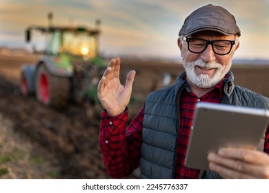 Excited mature farmer working on tablet in front of tractor in field - Powered by Shutterstock