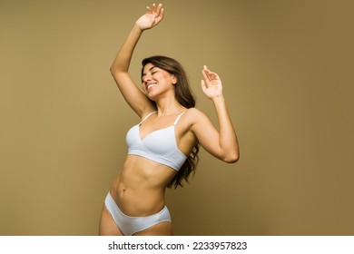 Excited mexican woman dancing and having fun in underwear in front of a studio background
