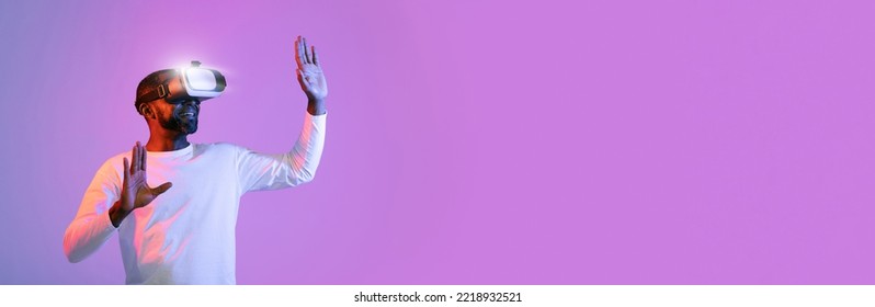 Excited middle aged black man in white using VR glasses on neon studio background, touching something invisible with hands, panorama, copy space. Modern technologies, entertainment, virtual reality - Powered by Shutterstock