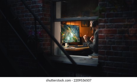 Excited Middle Aged Male Gamer Playing Online Video Game On Personal Computer. Guy Enjoying Fantasy RPG Game With Role Playing Character Casting Magic Spells, Destroy Enemies. Shot From Outdoors.