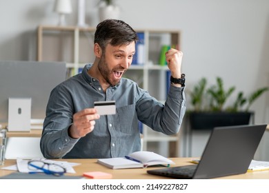 Excited Middle Aged Man Holding Credit Card In Front Of Laptop And Making YES Gesture, Paying For Goods And Services On Web, Shopping While Sitting In Office. Cool Online Promo Concept