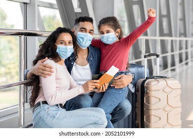 Excited Middle Eastern Parents And Little Child In Medical Face Masks Waiting For Flight At Airport Terminal, Happy Arab Family Of Three Enjoying Safe Travels During Coronavirus Pandemic, Copy Space