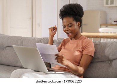 Excited Millennial African American Woman Sitting On Couch At Home, Holding And Reading Paper Document, Feel Euphoric. Black Girl Receiving Job, Enjoy Exam Results Or College Admission Letter.