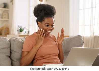 Excited Millennial African Woman Relax On Couch At Home, Get Pleasant Online Message On Laptop, Receive Unexpected Good News Or Email, Screaming With Joy. Black Young Girl Triumph Win Lottery.