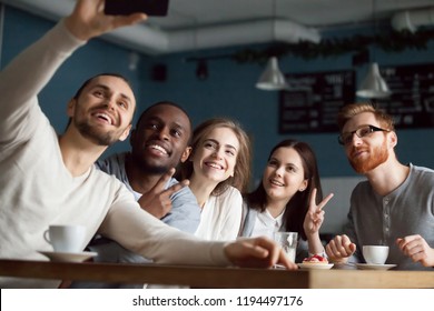 Excited millennial friends make selfie on smartphone having fun in coffeeshop, happy students smile for picture on phone meeting together in café, diverse young people posing for self-portrait - Powered by Shutterstock