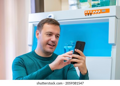 Excited Millennial Scientist Showing Emotions Of Joy About Victory In Online Lottery In Room With Laboratory Box In UV Light. Worker Of Scientific Laboratory Win Money Celebration Success And Sit