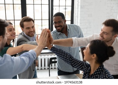 Excited millennial teammates joining hands for giving high fives. Team of happy employees celebrating corporate goal achievement, successful project accomplishment, shared success. Teamwork concept