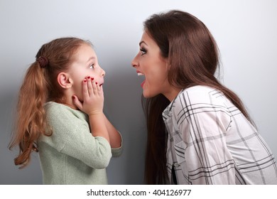 Entusiasmada madre y niña sorprendida mirándose entre ellos con la boca abierta de fondo azul
