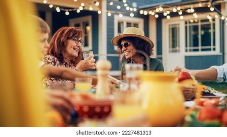 Excited Multiethnic Female Chatting with a Senior Woman at a Summer Garden Party. Happy Diverse Group of Children, Adults and Older People Gathered at a Table to Have Fun and Enjoy Food. - Powered by Shutterstock