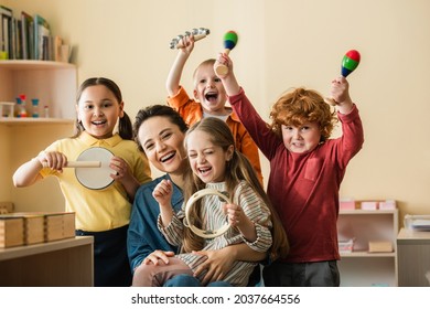 excited multiethnic kids playing musical instruments near happy teacher - Shutterstock ID 2037664556