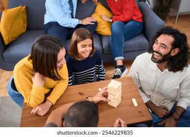 Excited multi-generational family gathering playing Jenga at home. Caucasian together making domestic life with board games. Woman is taking a block of wood out of tower and it falls. Digital detox - Powered by Shutterstock