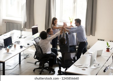 Excited multiracial office workers team giving high five together, celebrating successful teamwork results, involved in team building activity, good corporate relations, motivated by success